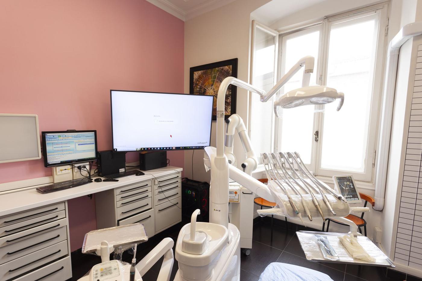 Una sala di cura dalla parete rosa, con il riunito e il monitor
